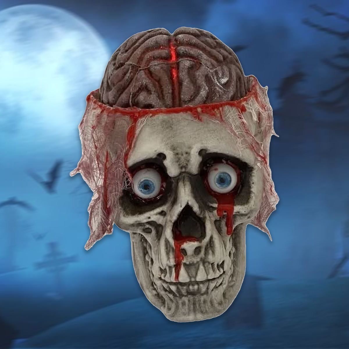 A Halloween skull prop with a realistic brain attached to its head, featuring bloody tattered bandages around the forehead and blue eyeballs, set against a spooky blue night sky background with a full moon.