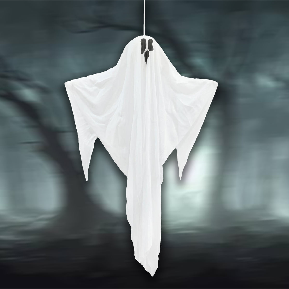 A white ghost-shaped Halloween decoration or costume sheet hanging from a thin cord against a dark, misty forest background.